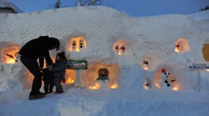 ろうそくの明かりがともされ、雪だるまの姿が浮かび上がる「雪だるままつり」（朝日新聞）